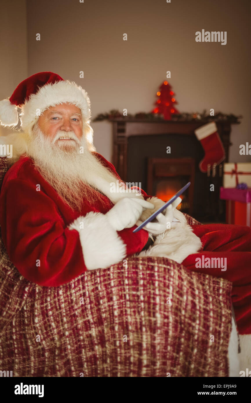 Cheerful santa touching tablet on the couch Stock Photo - Alamy