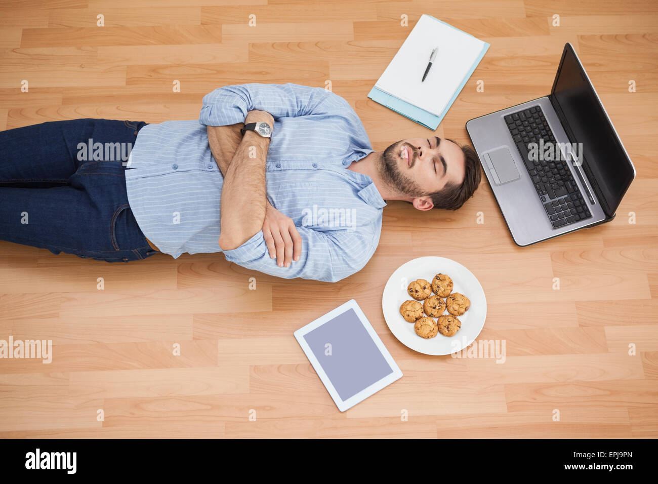Casual man lying on floor surrounded by his possesions Stock Photo