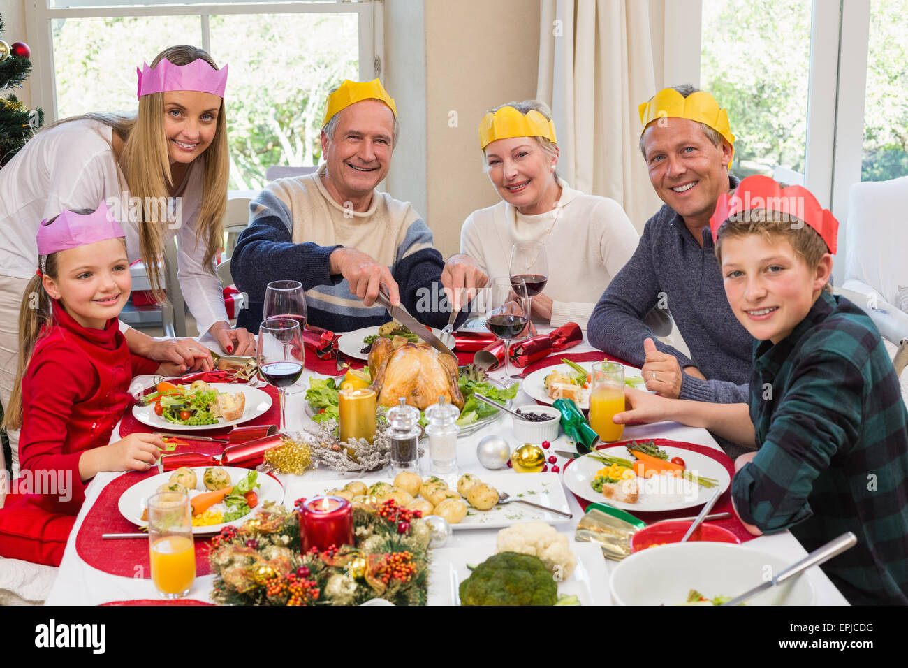 Grandfather in party hat carving chicken during dinner Stock Photo Alamy