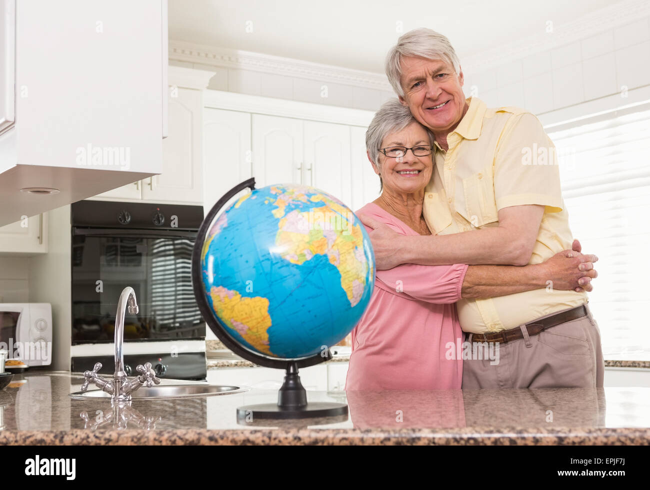 Senior couple smiling at the camera together with globe Stock Photo
