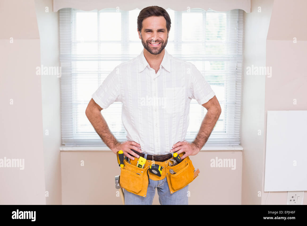 Handyman smiling at camera in tool belt Stock Photo