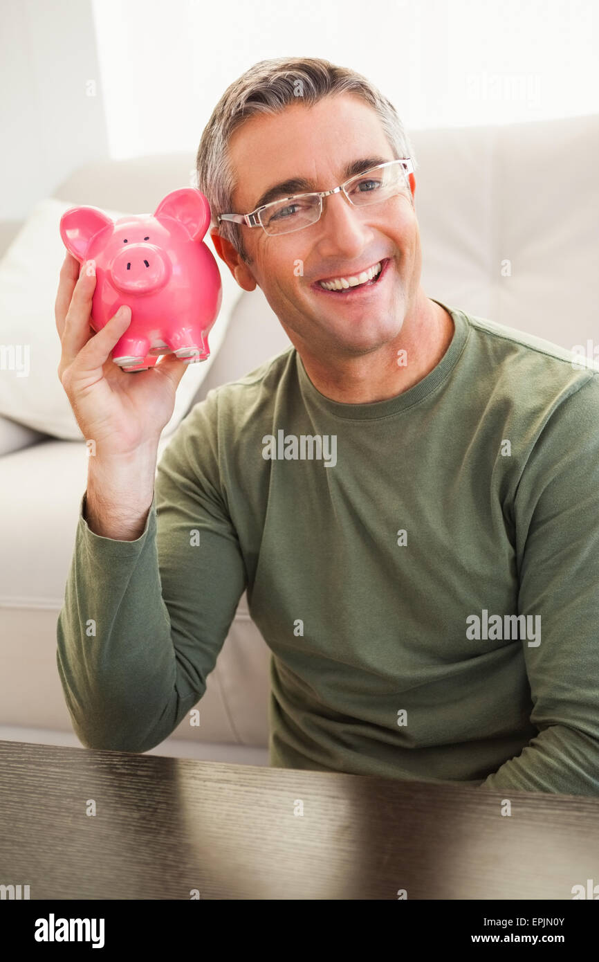Smiling man posing with a piggy bank Stock Photo - Alamy