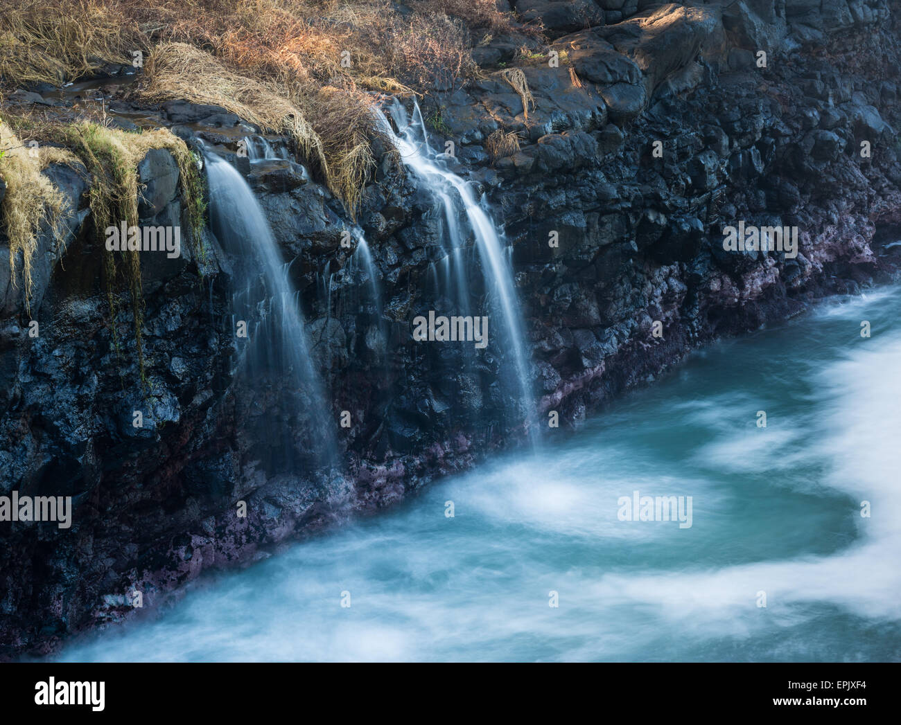 Waterfall flows into sea at Queens Bath Kauai Stock Photo - Alamy