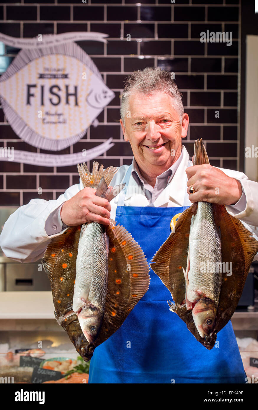A fishmonger at his counter with Plaice and Sea Bass UK Stock Photo