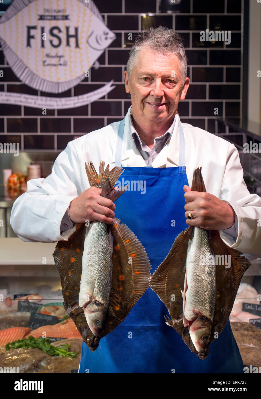 A fishmonger at his counter with Plaice and Sea Bass UK Stock Photo