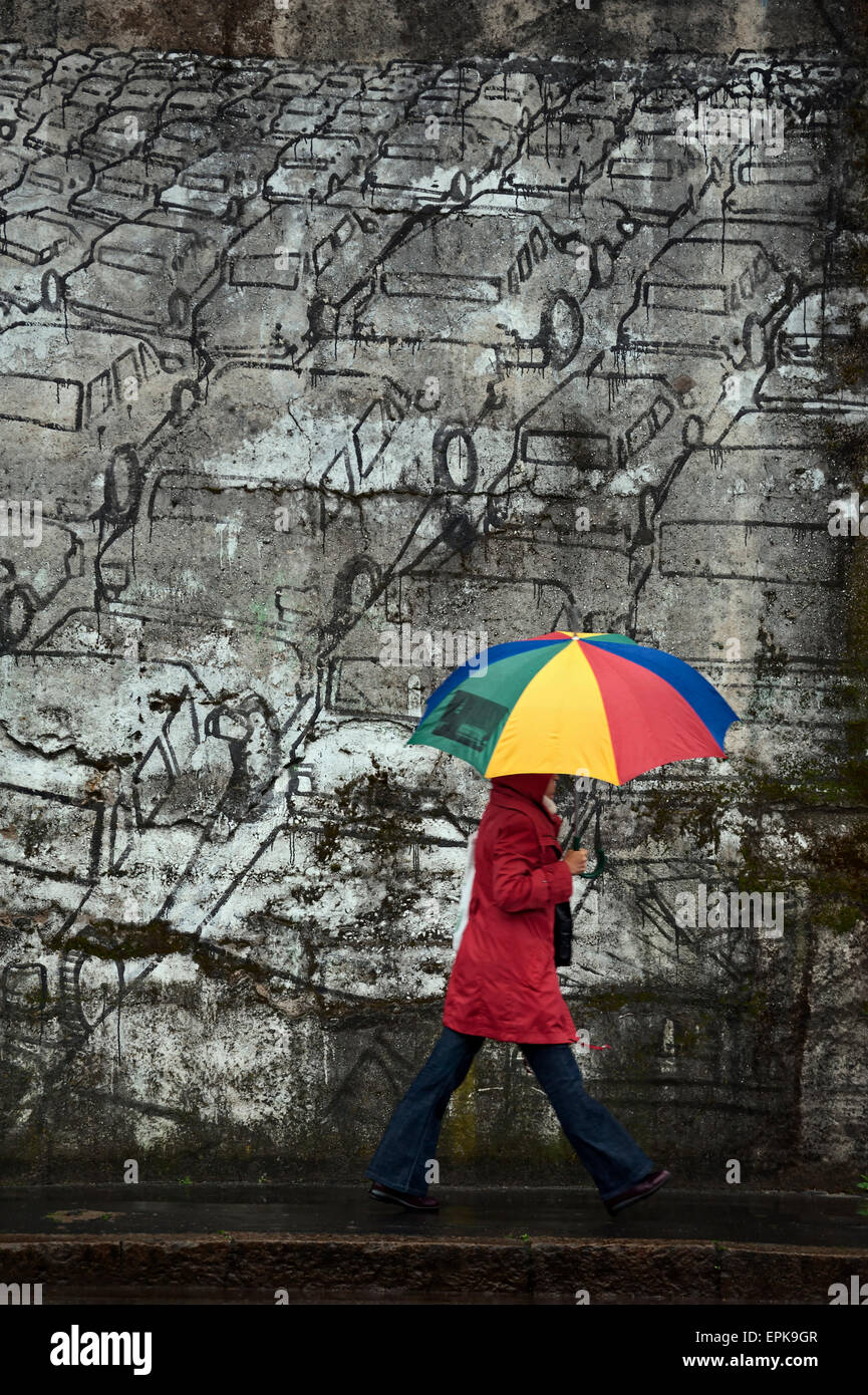Woman with umbrella walking near a mural Stock Photo