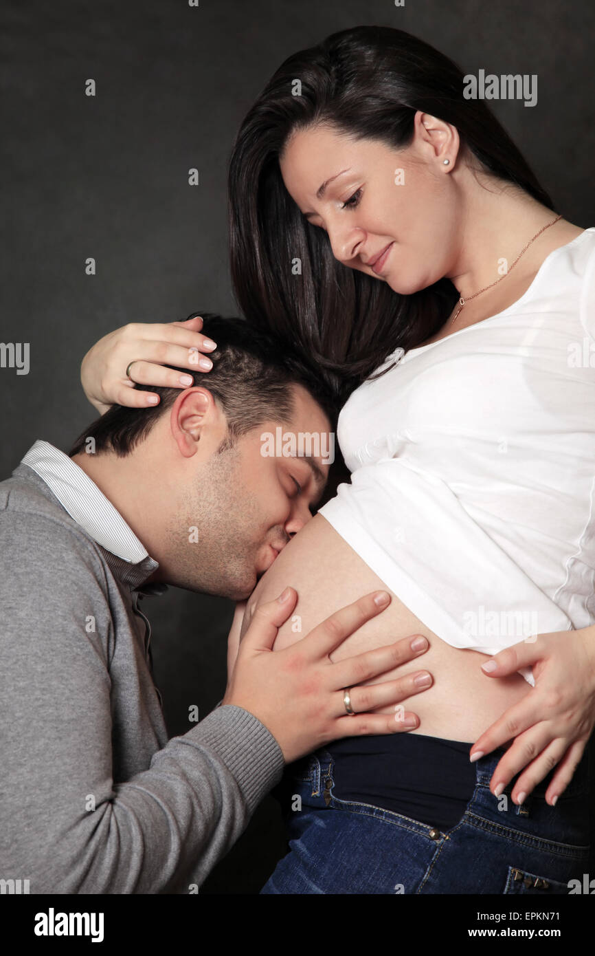 Целует беременную жену. Муж целует животик беременной жены. Обнимает беременную. Целует беременных девушек. Фотосессия беременного мужчины.