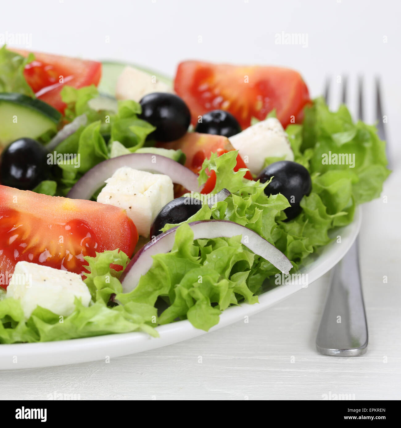 Griechischer Salat essen mit Tomaten, Feta K├ñse und Oliven in Sch├╝ssel mit Gabel Stock Photo