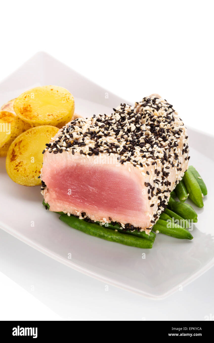 Grilled tuna steak wrapped in black and white sesame seeds on green