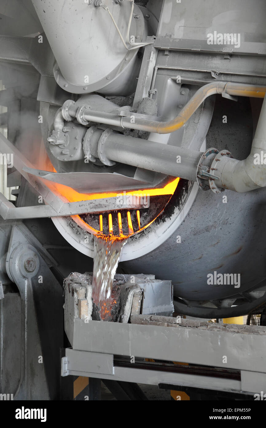 Molten aluminium flows from a metal recovery furnace in a large aluminuim smelting plant Stock Photo