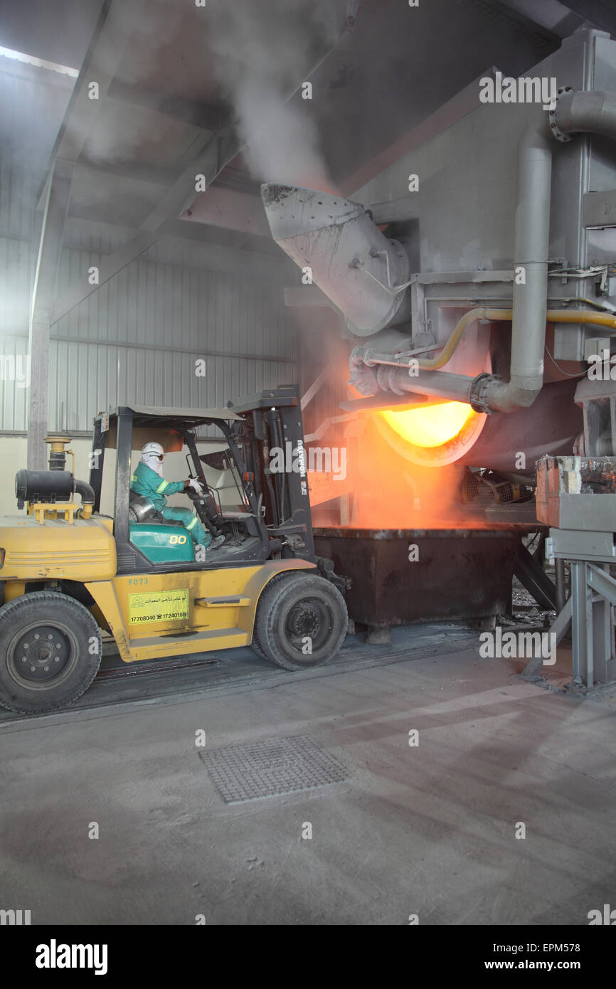A fork lift truck collects waste material from an aluminium recovery furnace in a large aluminium smelting plant Stock Photo