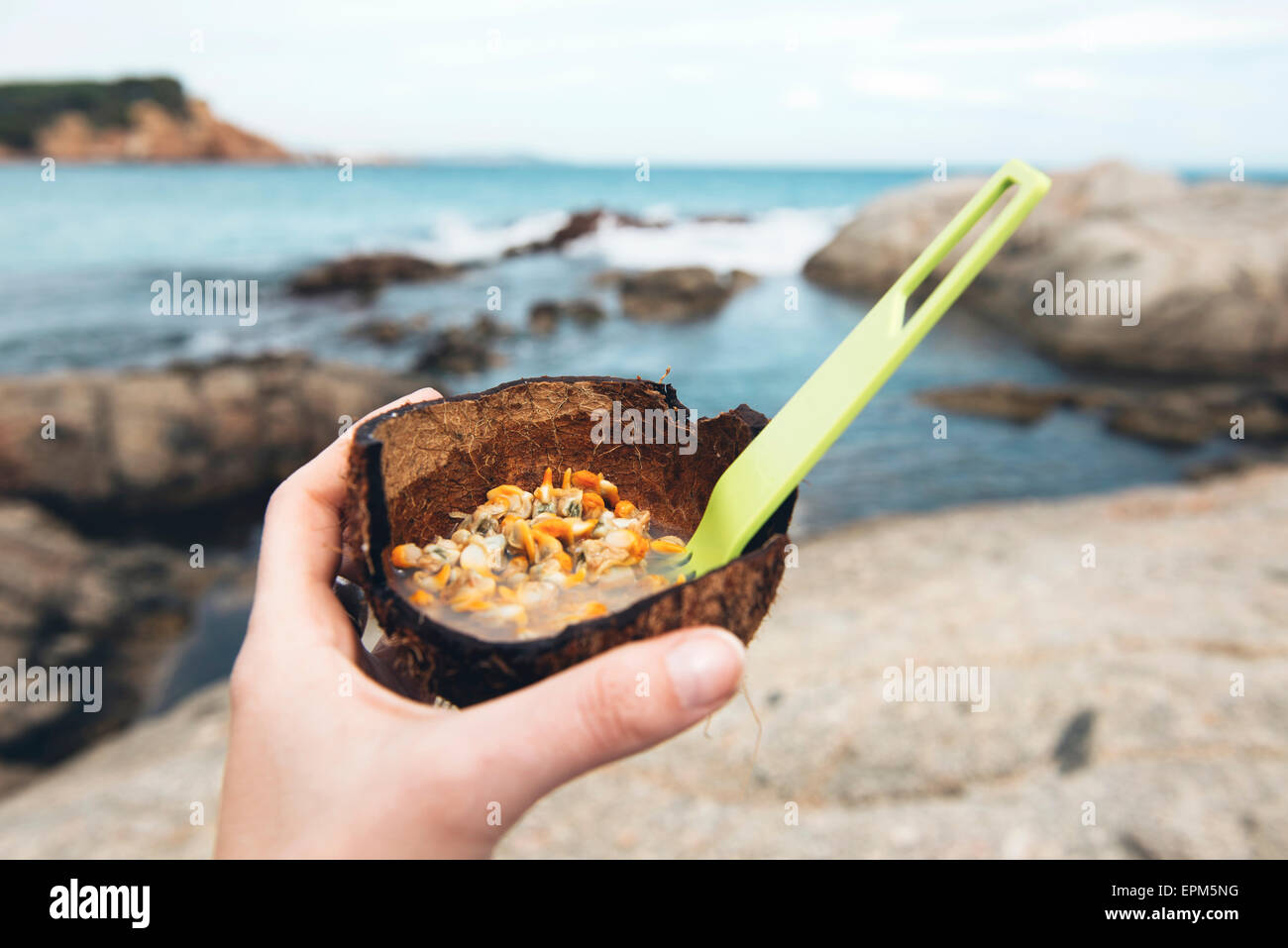 Spain, Costa Brava, woman's hand holding coconut shell with cockles Stock Photo