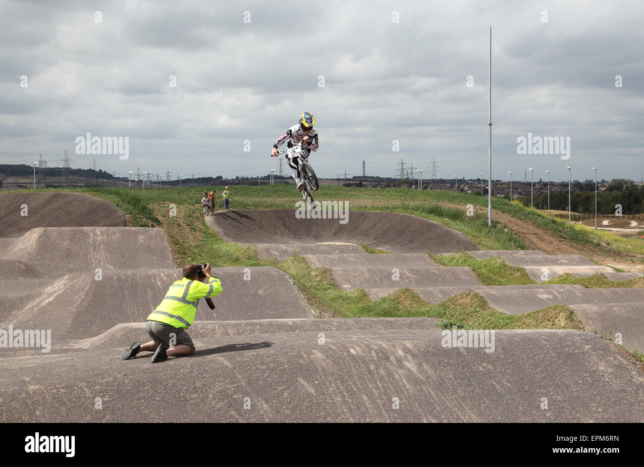 A photographer shoots a BMX bike rider as they perform a jump at the Gravesend Cyclopark, Kent, UK. Stock Photo