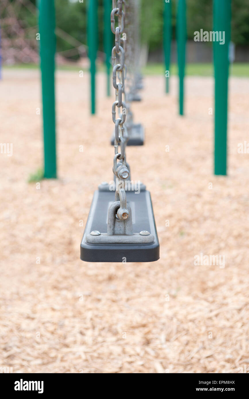 An empty row of swings at a public playground park Stock Photo