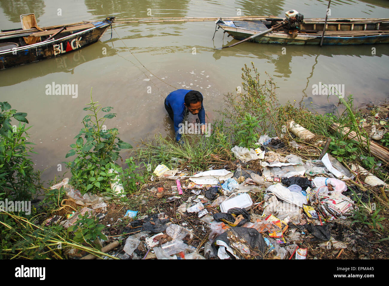 Tangerang, Indonesia. 18th July, 2014. Dodi (38 years old), who works as a Silkworm seekers (Tubifex), is looking for silk worms at Cisadane River, Tanah Gocap, Tangerang. Dodi day can get 25-30 cans per tin silk worms for 5 thousand and sold in fish stores in Tangerang. © Garry Andrew Lotulung/Pacific Press/Alamy Live News Stock Photo