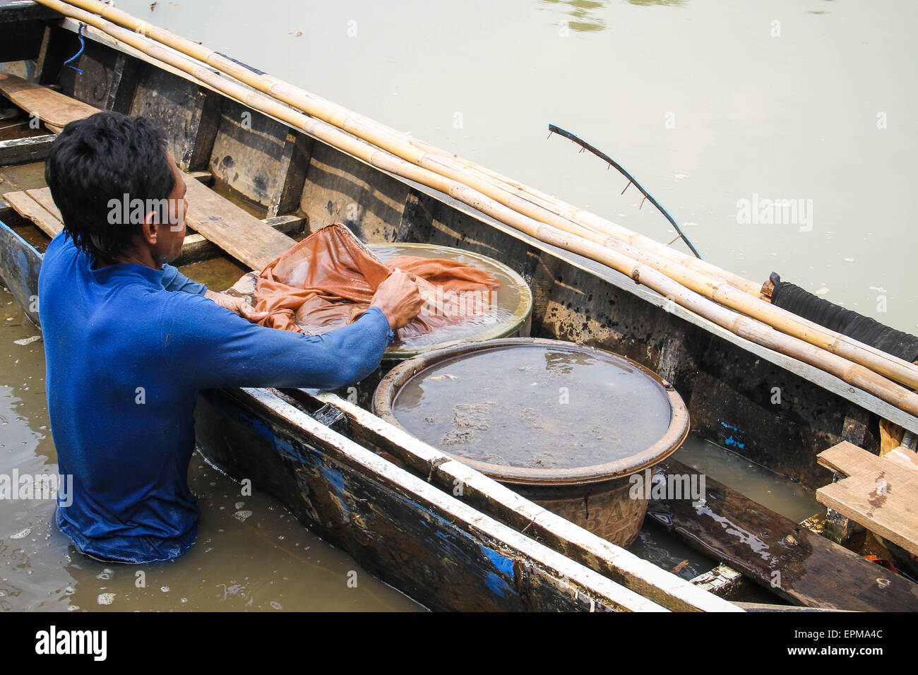 Tangerang, Indonesia. 18th July, 2014. Dodi (38 years old), who works as a Silkworm seekers (Tubifex), is looking for silk worms at Cisadane River, Tanah Gocap, Tangerang. Dodi day can get 25-30 cans per tin silk worms for 5 thousand and sold in fish stores in Tangerang. © Garry Andrew Lotulung/Pacific Press/Alamy Live News Stock Photo