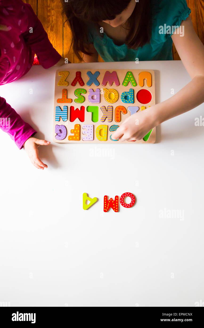Two sisters with with wooden alphabet puzzle Stock Photo
