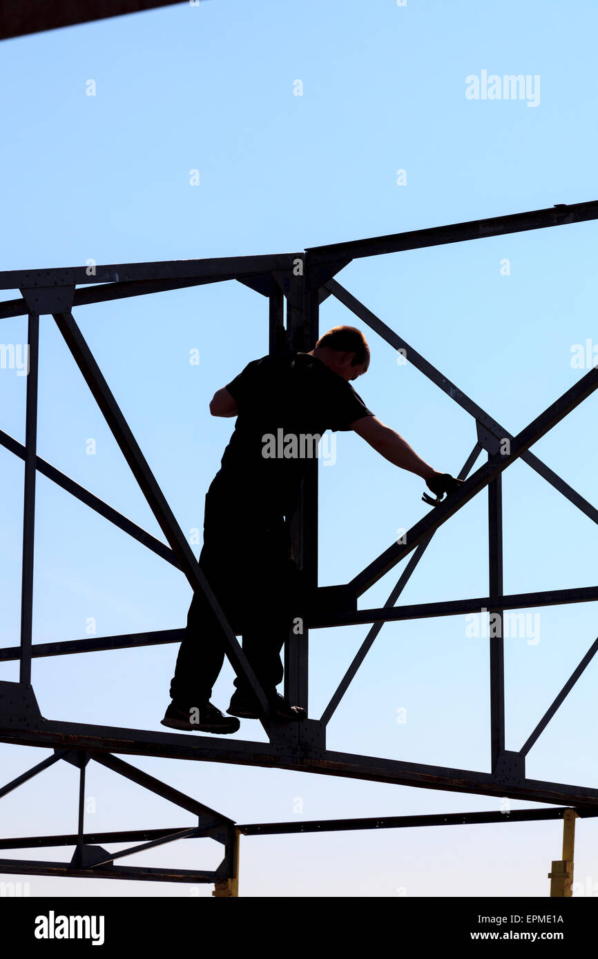 Rigger working amongst steel framework without safety equipment Stock Photo