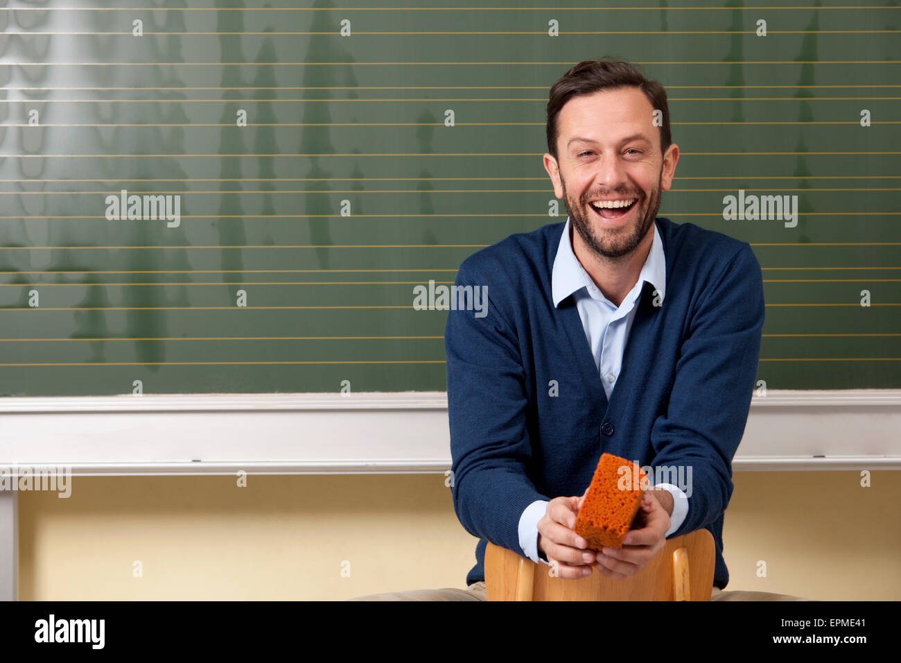 Laughing teacher in classroom at blackboard Stock Photo