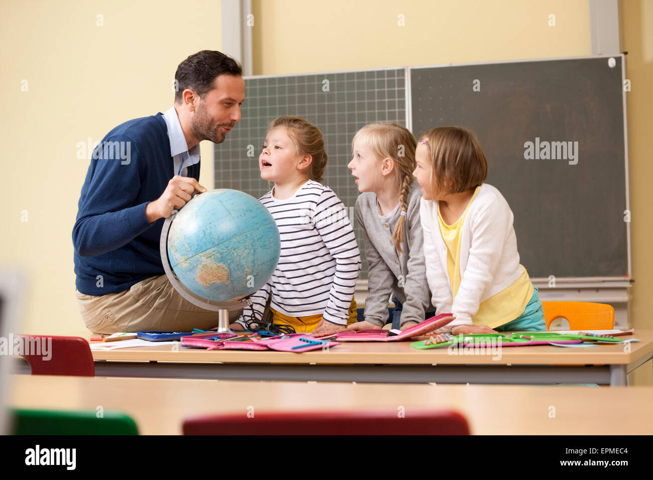 Teacher and pupils with globe in classroom Stock Photo - Alamy