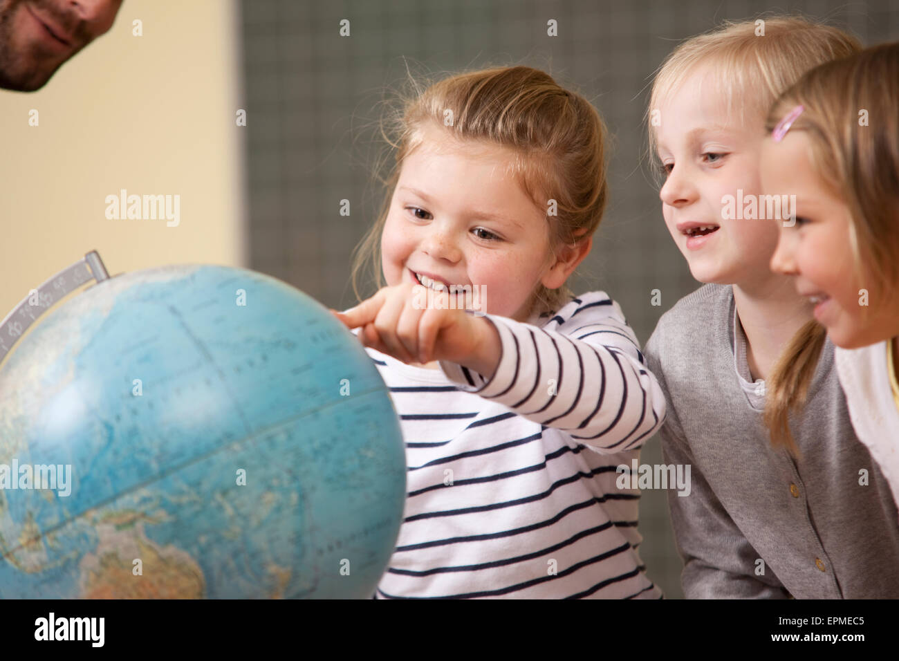 Smiling schoolgirls pointing at globe in classroom Stock Photo - Alamy