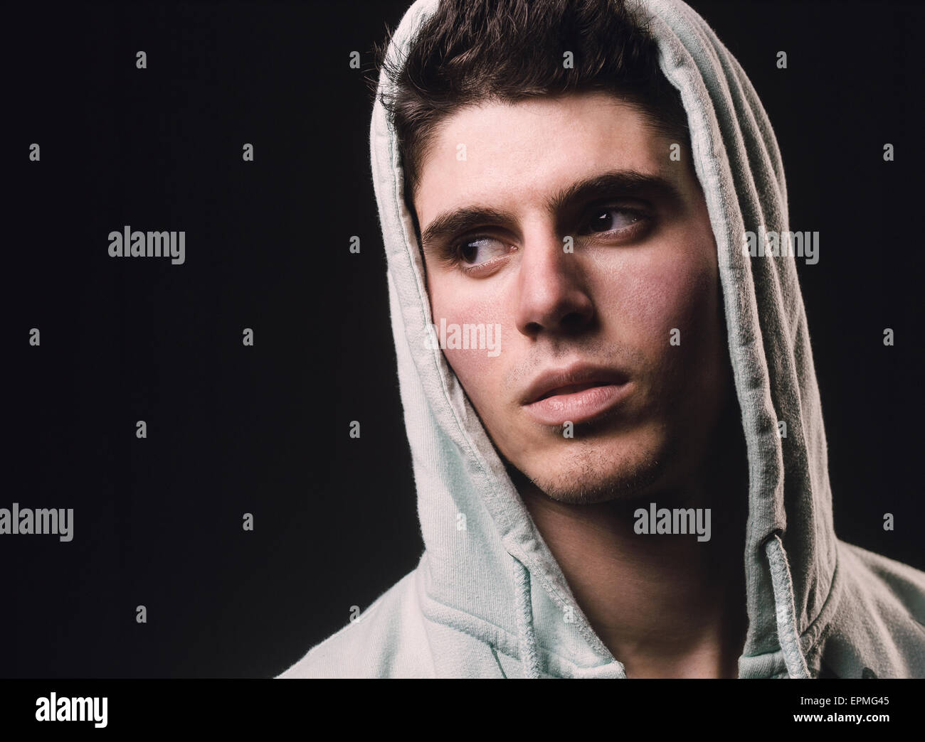 Portrait of man wearing hooded jacket in front of black background Stock Photo