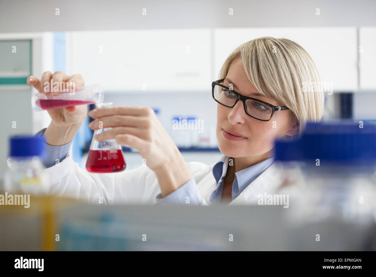 Scientist pouring liquid in Erlenmeyer flask Stock Photo