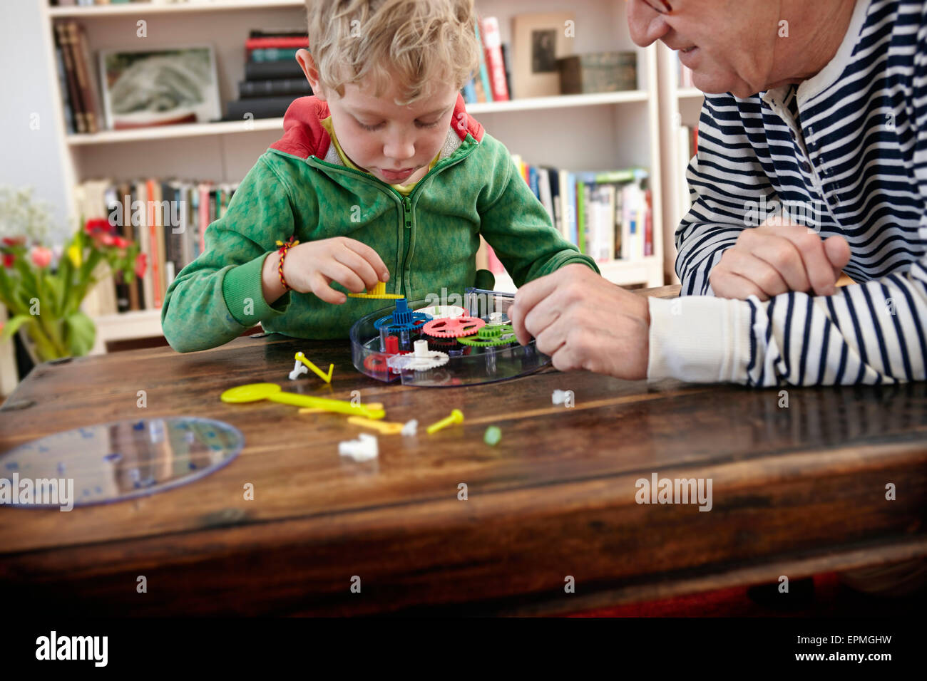 Grandfather and grandson assembling toy clock Stock Photo