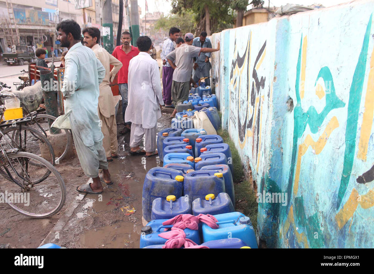 Water shortage in the metropolitan continues as residents of different areas have no option but to buy water on hiked price, in photo residents of Mehmoodabad can be seen filling their pots and empty gallons with water due to water crises in their locality on Tuesday, May 19, 2015. Stock Photo