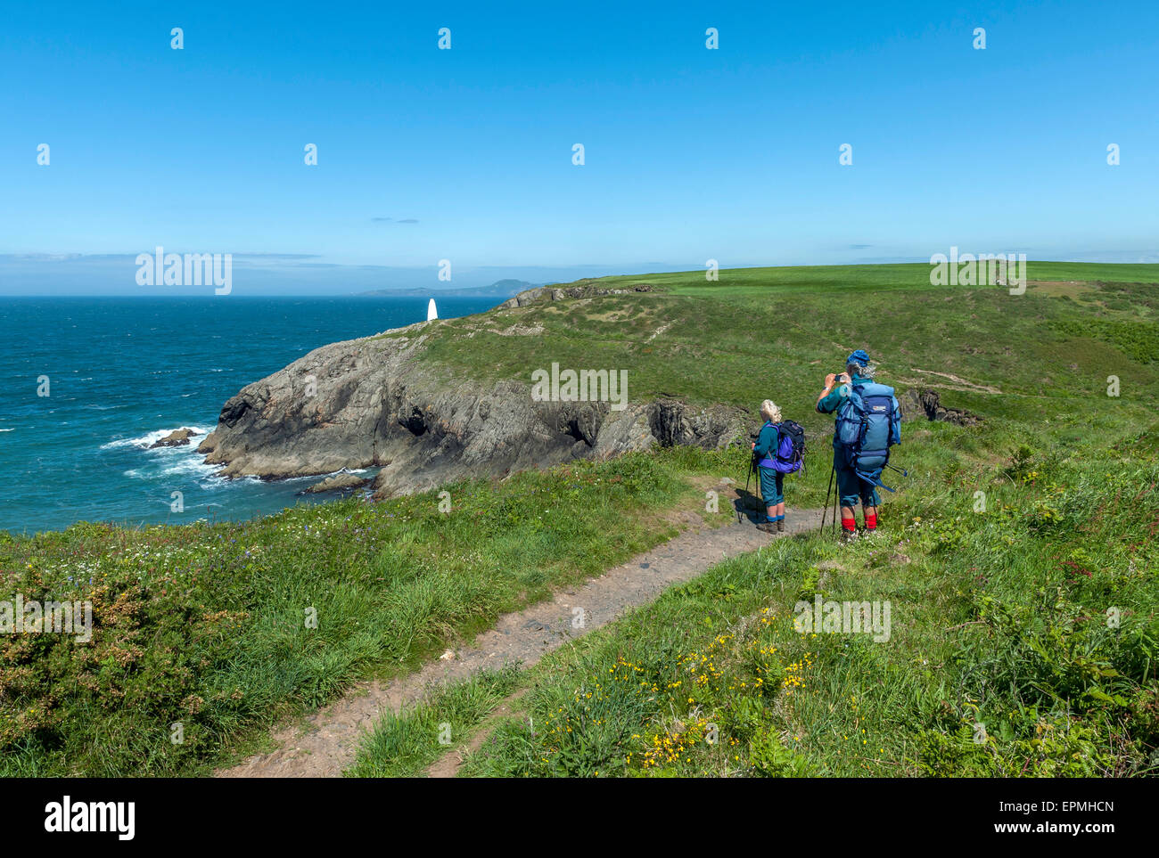 A couple of mature hikers along the Pembrokeshire coastal path near Porthgain. Pembrokeshire. Wales. Cymru. UK Stock Photo