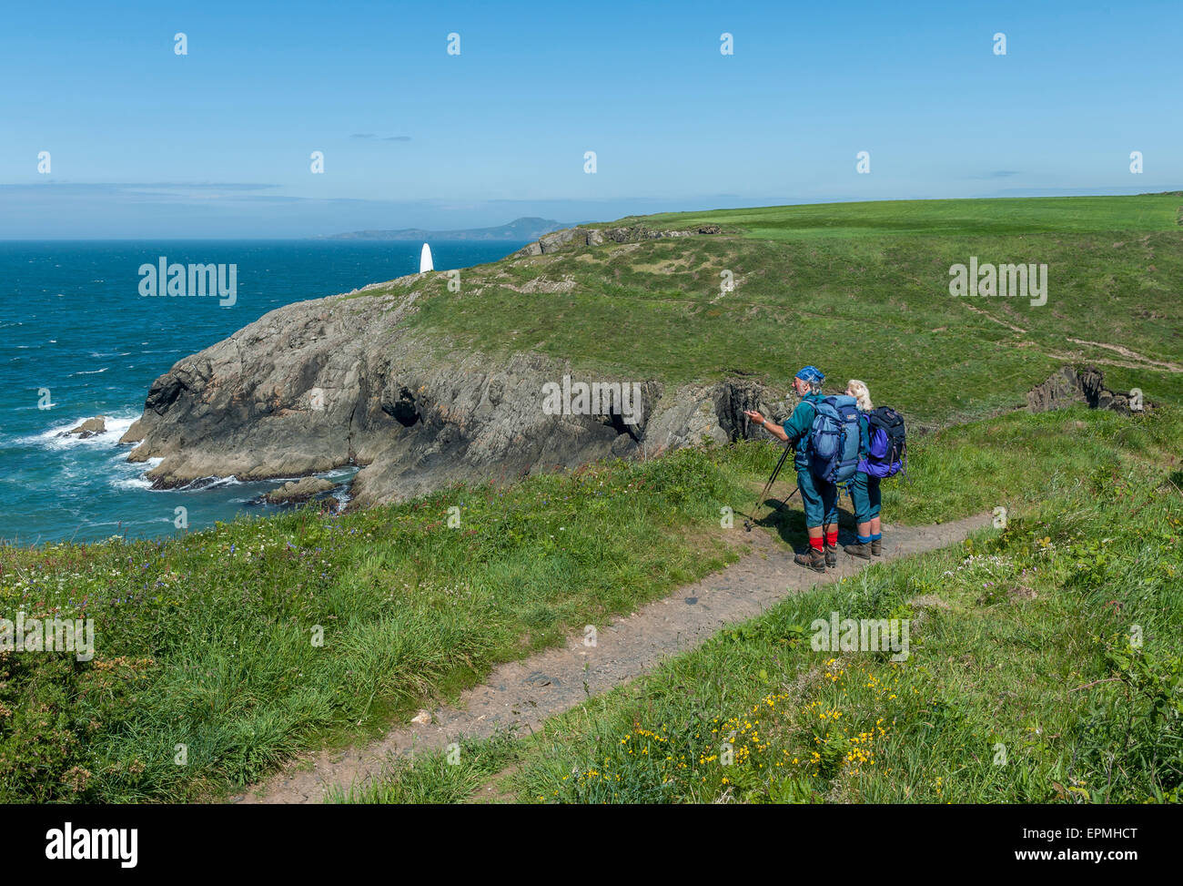 A couple of mature hikers along the Pembrokeshire coastal path near Porthgain. Pembrokeshire. Wales. Cymru. UK Stock Photo