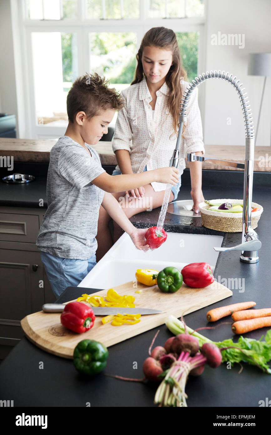 Brother and sister washing vegetables in kitchen Stock Photo Alamy