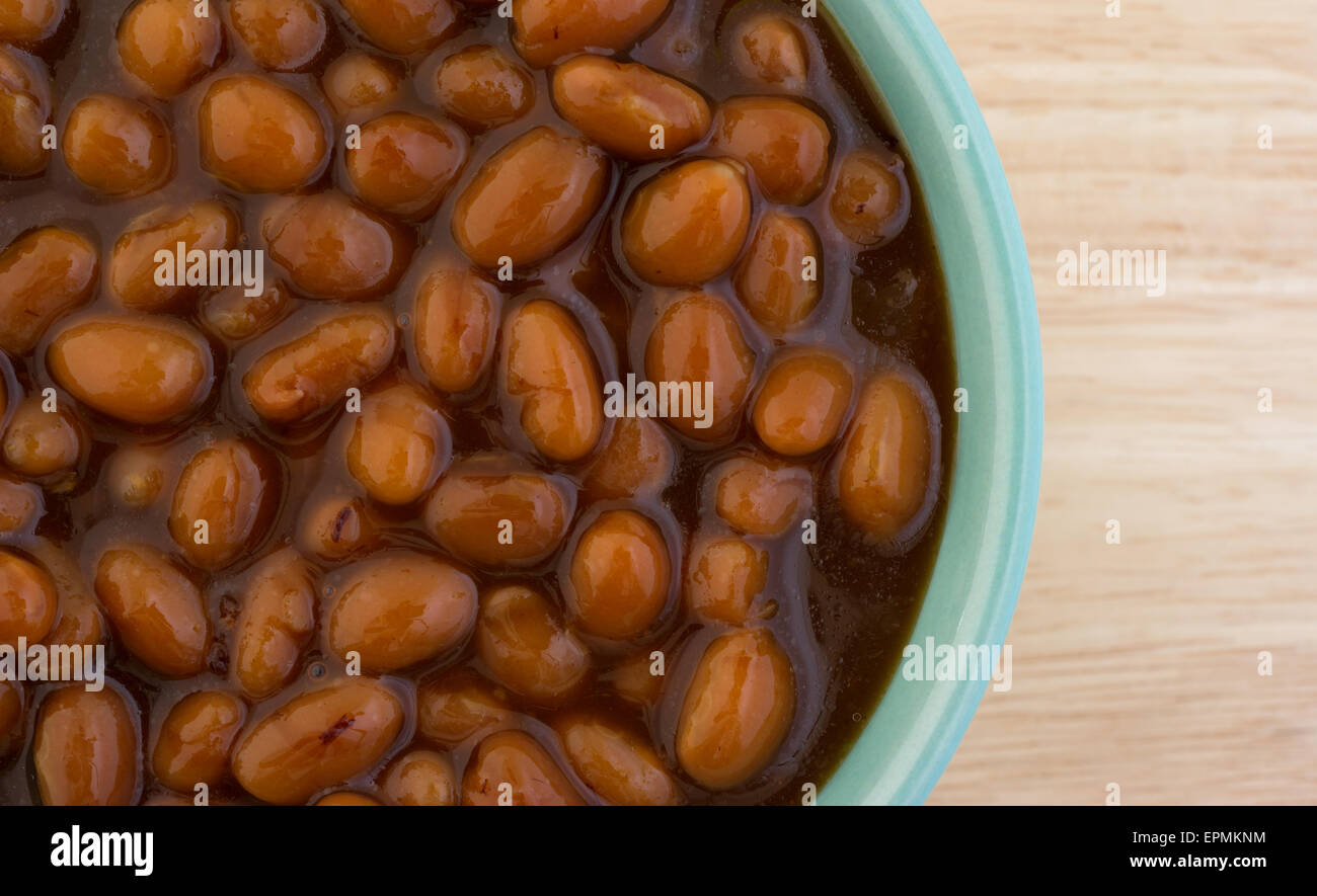 Close view of a bowl of country style baked beans in a small bowl atop a wood table top. Stock Photo