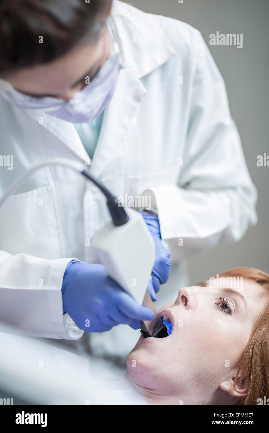 Female dentist preparing tooth whitening with blue light Stock Photo