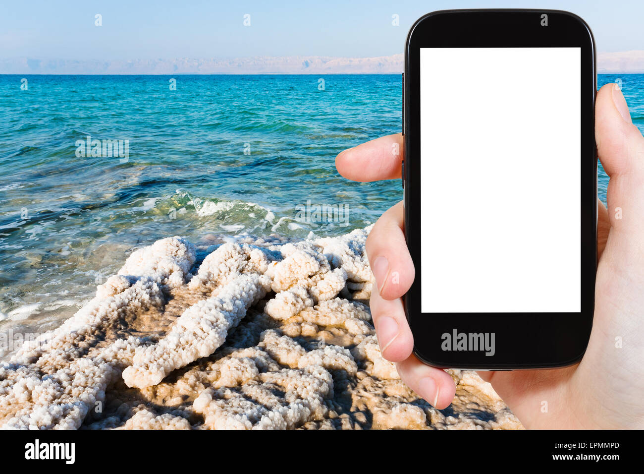 travel concept - tourist photograph crystalline coastline of Dead Sea, Jordan on tablet pc with cut out screen with blank place Stock Photo