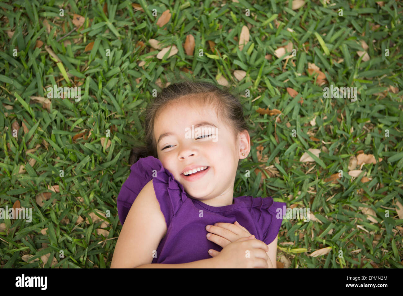 A child lying on her back on the grass. Stock Photo