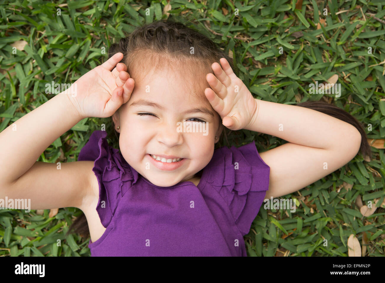 A girl lying on the grass with her hands by her head, laughing Stock ...