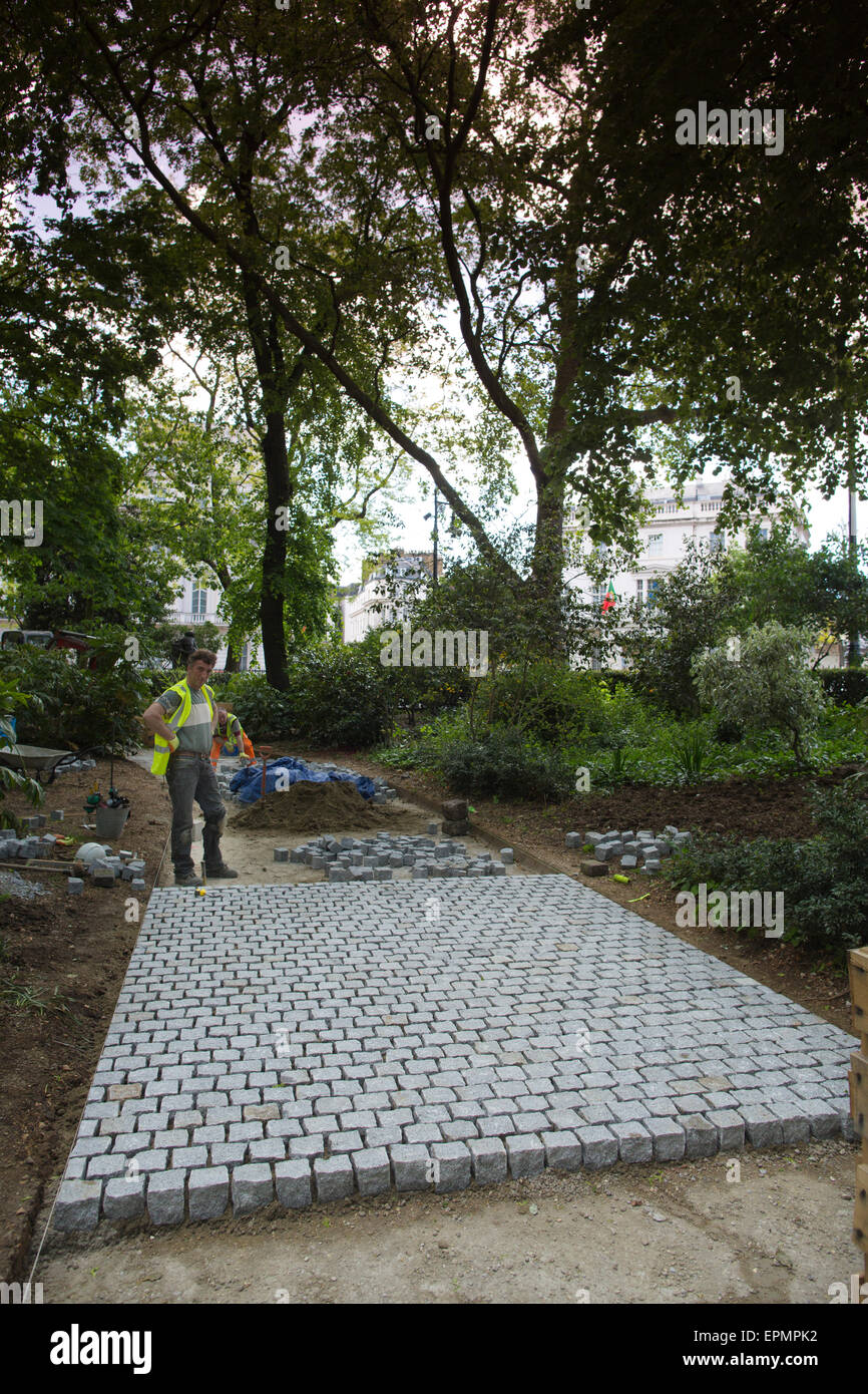 A worker laying a new path inside Belgrave Square Garden, Grosvenor ...