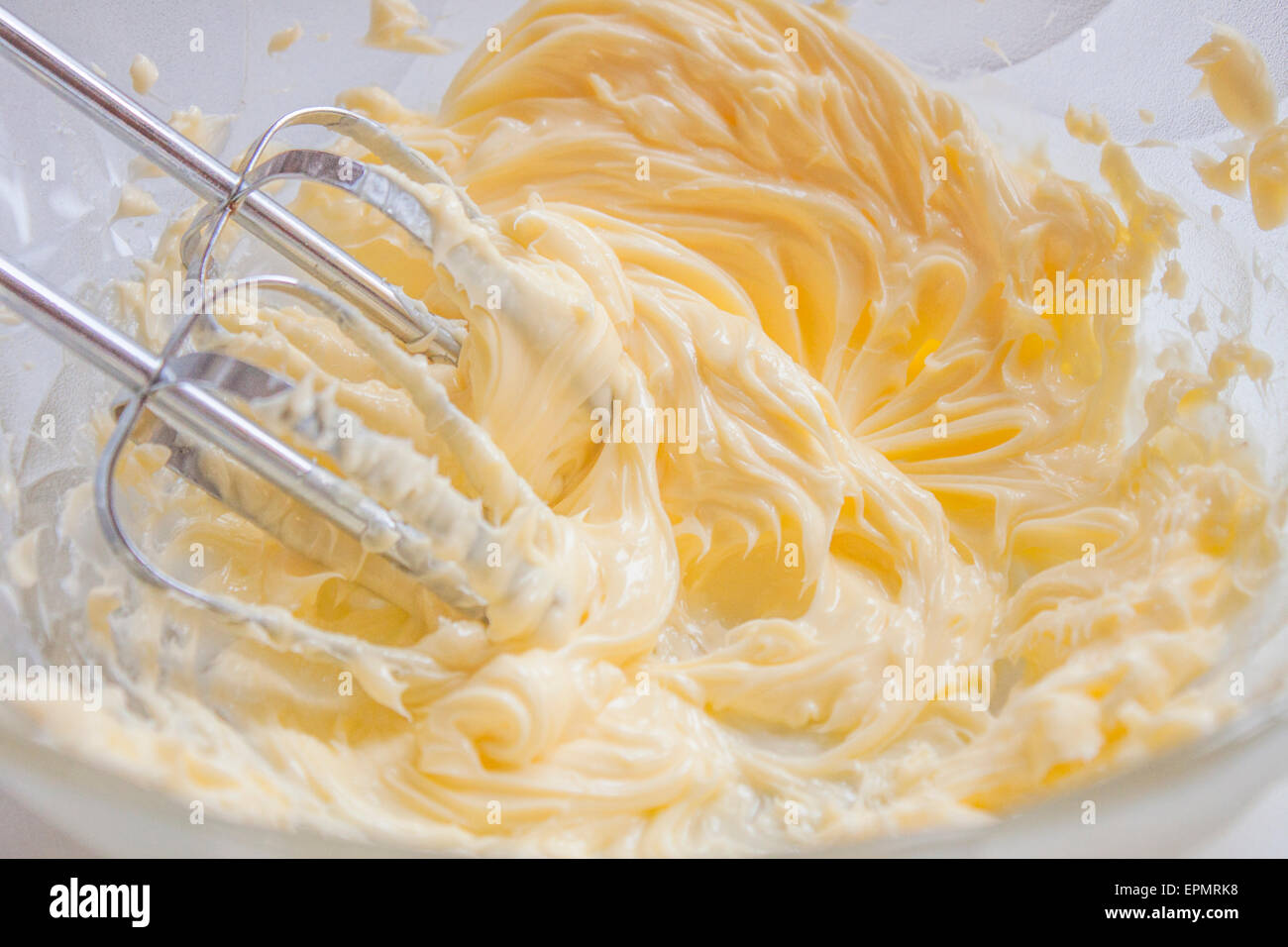 Whisking butter, in a bowl full of butter and egg yolks Stock Photo