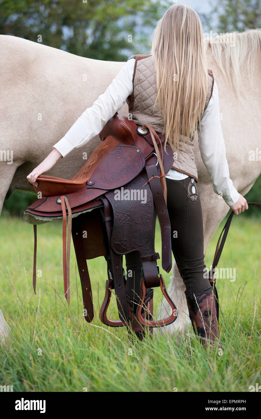 A young woman holding a western saddle Stock Photo