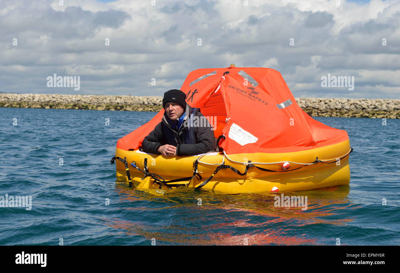 Portland Harbour, Dorset, UK. 18th May, 2015. A former soldier is hoping his seven days and nights in a life raft will be a lifeline to Great Ormond Street Hospital too in his unique fundraising effort.  His tiny life raft was towed out to a bouy and secured there in Portland Harbour today (mon) until next Monday as he started his survival period with just the items that one would have on such an emergency craft. Wayne Ingram, from Portland, has raised thousands of pounds for children around the world but now wants to do his bit for children in the UK. Credit:  Dorset Media Service/Alamy Live  Stock Photo