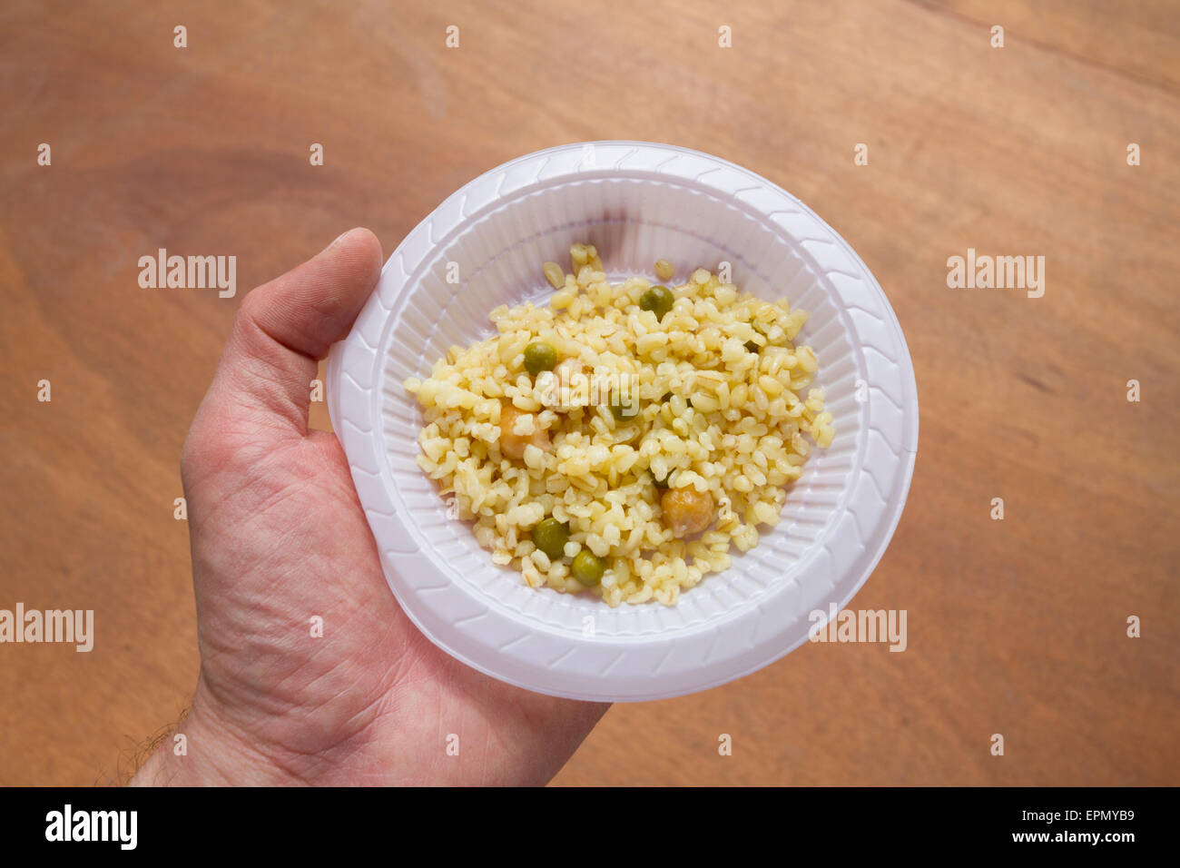 An hand holding a dish of Turkish bulgur seen from above Stock Photo