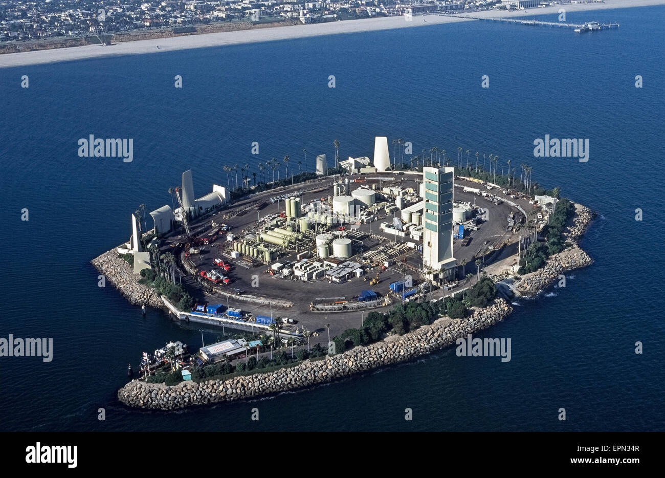 An aerial view shows one of four artificial islands where oil wells are operating just off shore in San Pedro Bay within sight of the city of Long Beach, California, USA. The novelty is that the storage tanks, derricks, pumps and other equipment necessary to extract crude oil from under the sea are camouflaged and soundproofed by tropical landscaping, waterfalls and building facades designed to resemble an island resort as seen from the city's shoreline. This is Island White, named for American astronaut Ed White who perished when his Apollo 1 spacecraft caught fire in 1967. Stock Photo