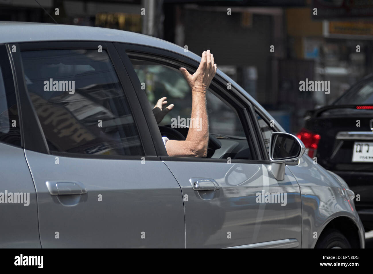 Frustrated driver. Motorist airing frustration at traffic delays constantly tapping hand on vehicle. Stock Photo