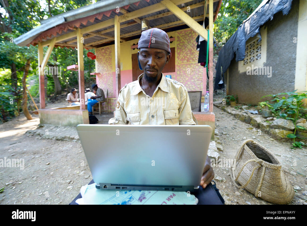 Man, 34 years old, sitting in front of his house with a laptop, Riviere Froide, Haiti Stock Photo