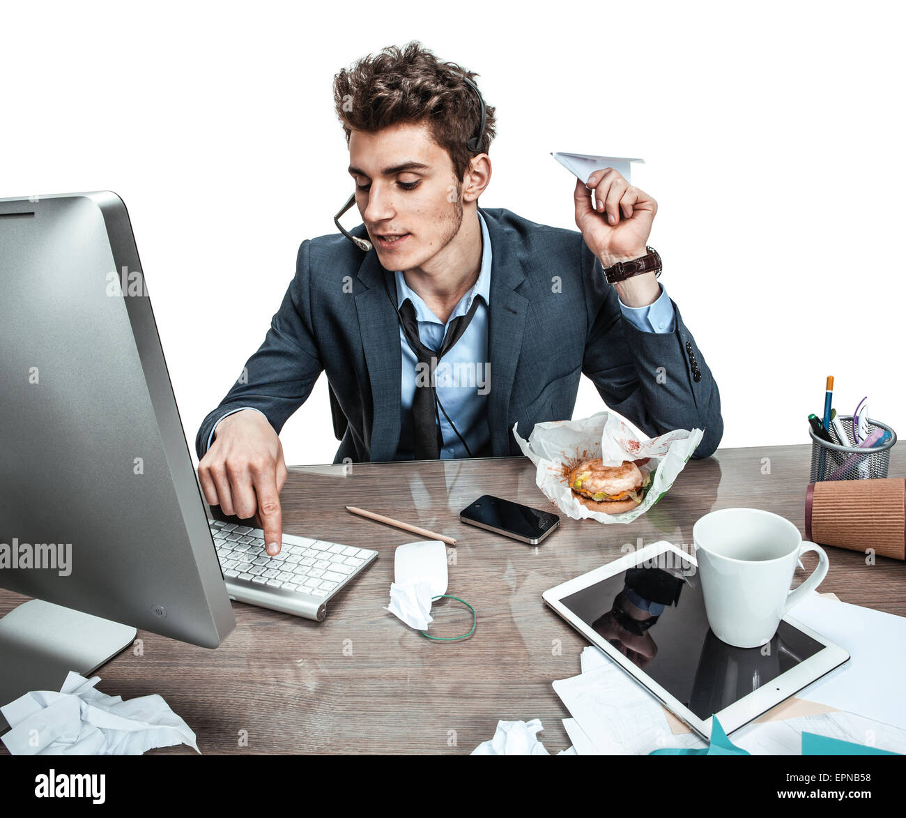 Guy with paper plane in his hand typing on a computer keyboard / modern office man at working place, sloth and laziness concept Stock Photo