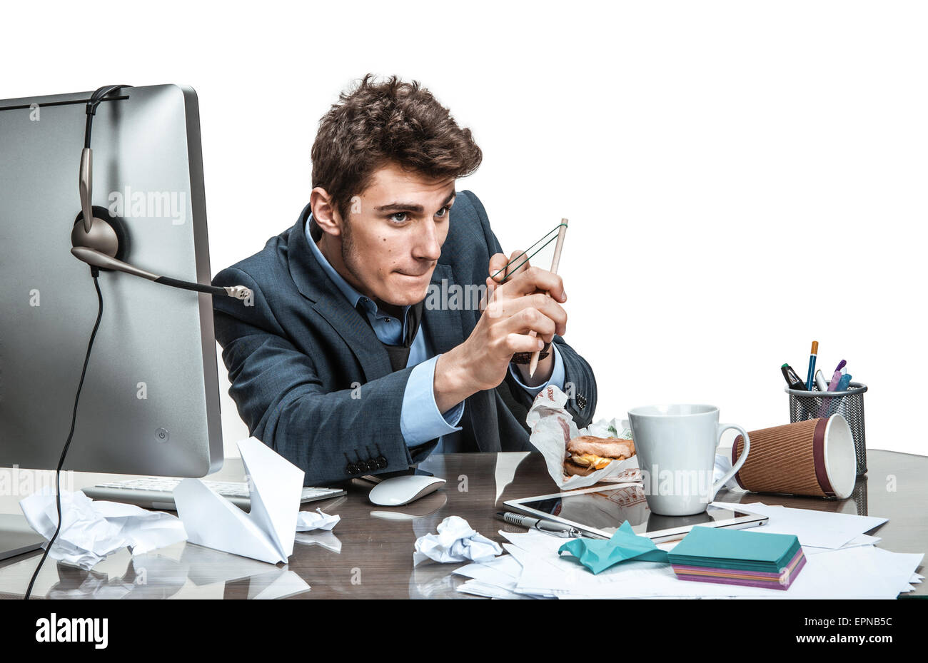 Concentrated man with slingshot aim / modern office man at working place, sloth and laziness concept Stock Photo