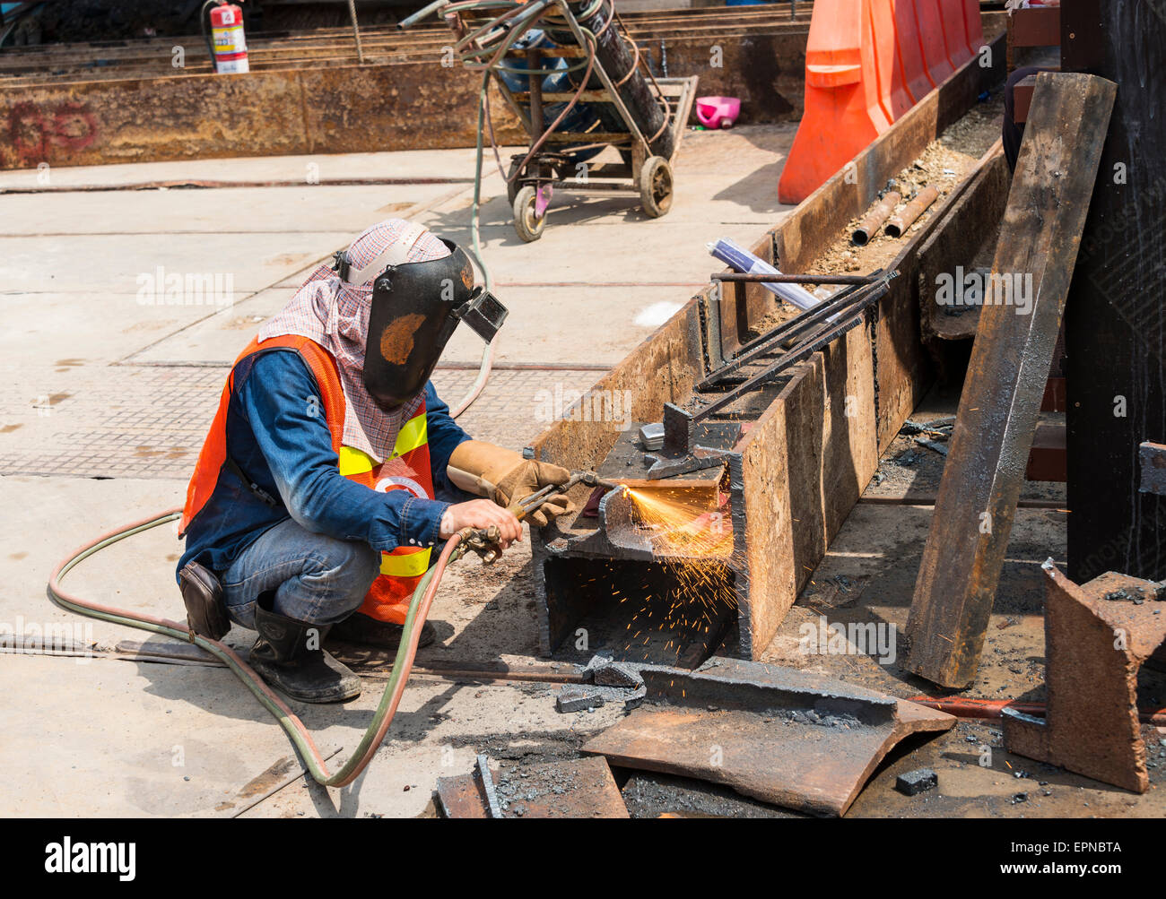 Construction worker welding a steel beam on a construction site, Bangkok, Thailand Stock Photo