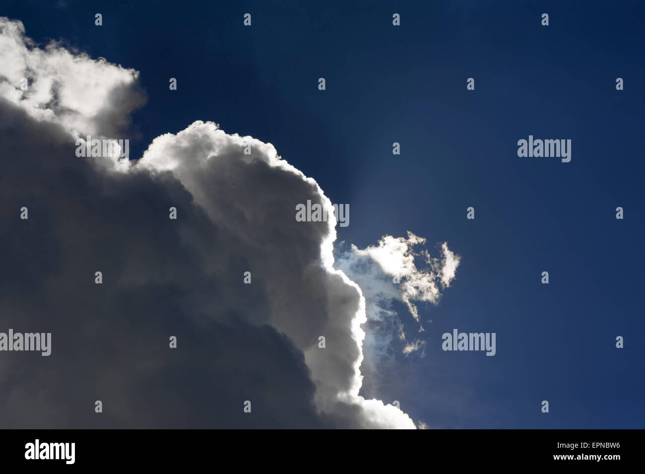 Rain clouds, nimbostratus, against a blue sky with bright sun rim Stock Photo
