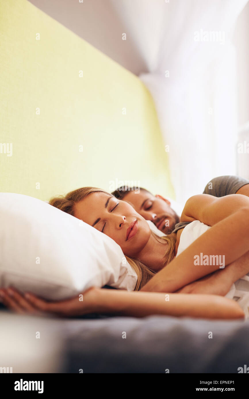 Indoor shot of young man and woman sleeping together in bedroom. Young caucasian couple sleeping on bed. Stock Photo